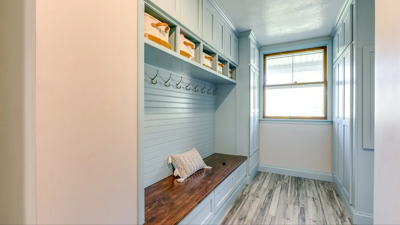 A blue mudroom with coat hooks and storage cabinets 