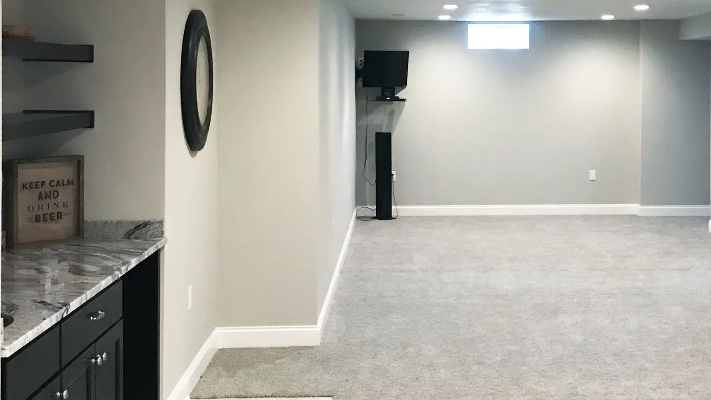 A basement remodel with light gray walls and carpet