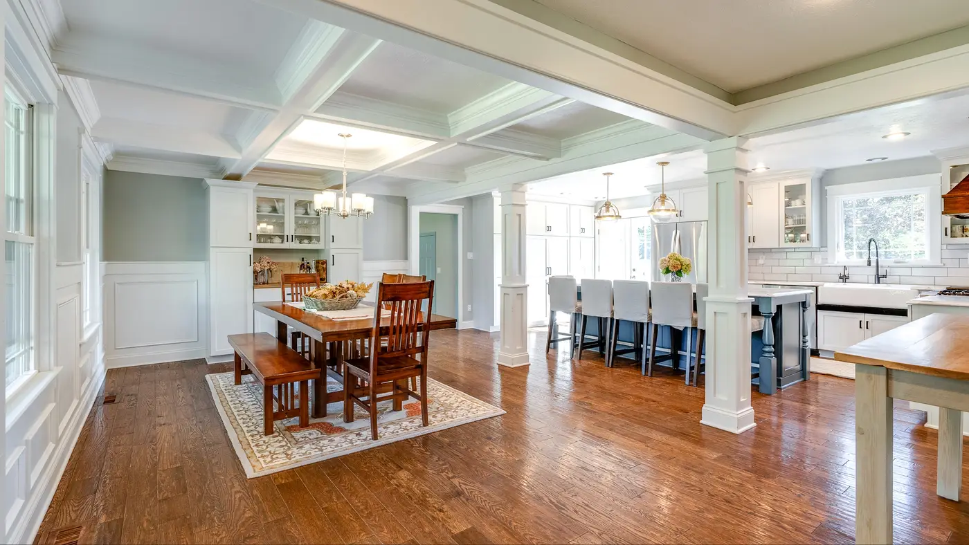 A large kitchen and dining room with intricate white walls with trim and brown wood flooring