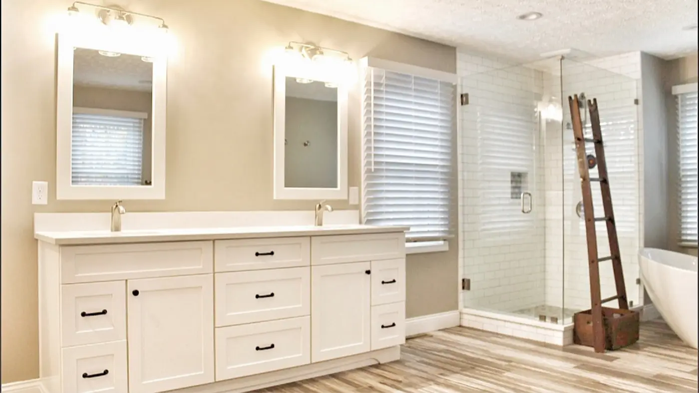 A bathroom with a white vanity and white mirrors, and a walk-in shower